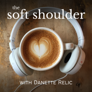 Aerial view of white headphones encircling a latte with a milk foam heart with the lettering "The Soft Shoulder with Danette Relic"